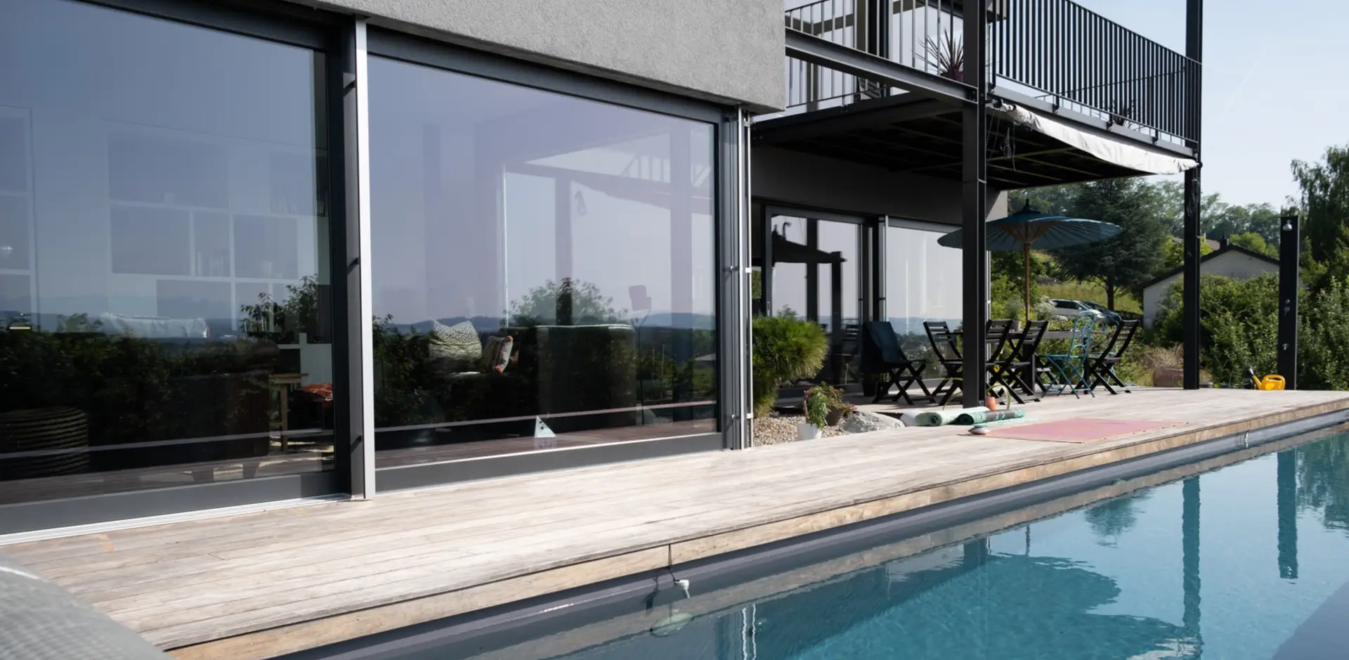 Terrasse et baies vitrées d'une maison moderne avec piscine.