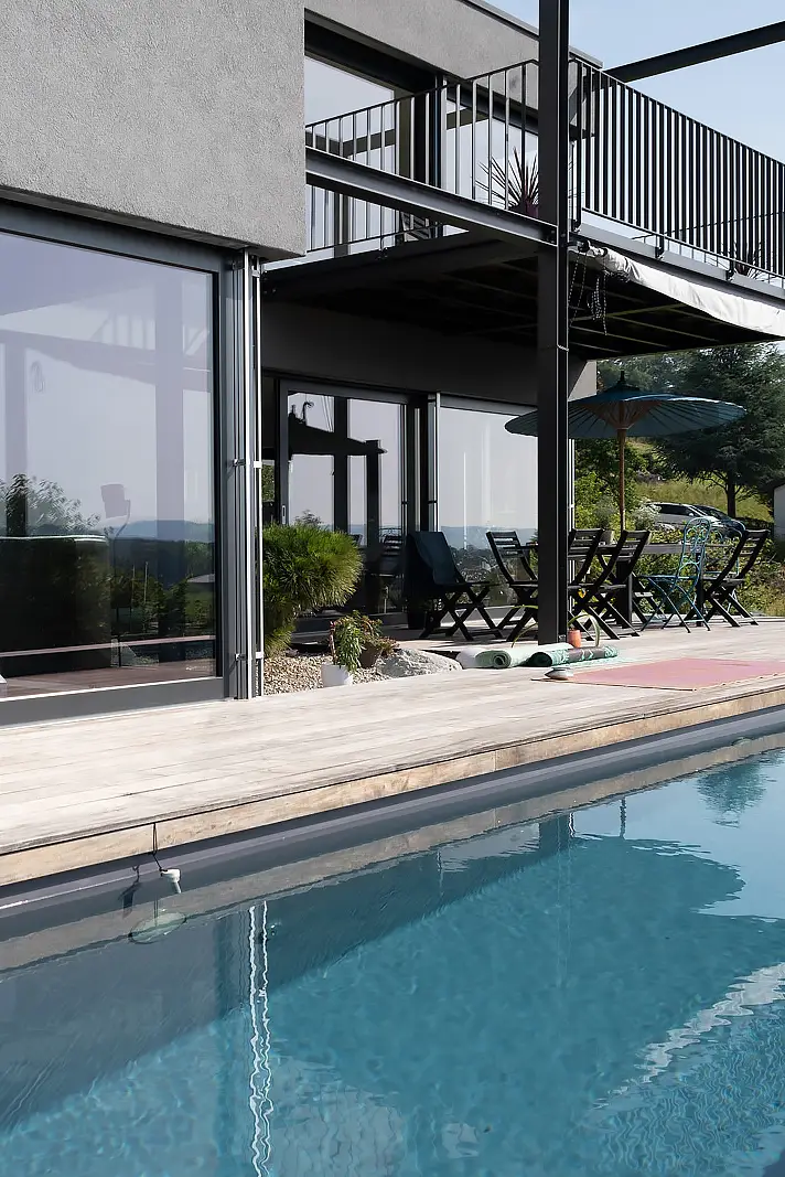 Maison moderne avec baies vitrées, piscine et balcon.